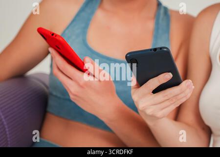 Zwei Frauen, die aktiv mit ihren Smartphones interagieren, in eine lebhafte Diskussion eintauchen und Gedanken austauschen, um die Verbindung und Interaktion zu demonstrieren Stockfoto