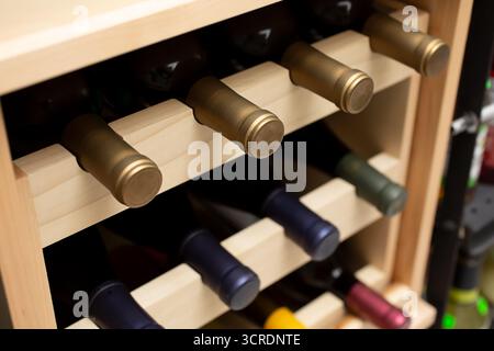 Blick auf mehrere Weinflaschen in einem hölzernen Weinregal. Stockfoto