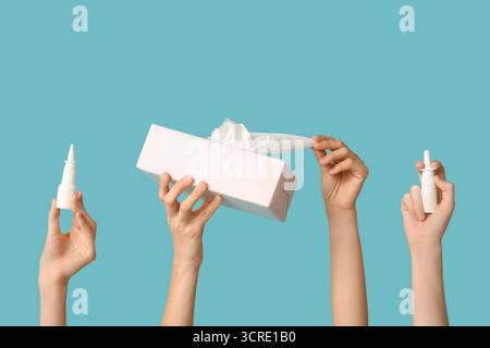 Weibliche Hände mit Flaschen Nasenspray und Tissue Box auf blauem Hintergrund Stockfoto