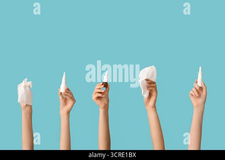 Weibliche Hände mit verschiedenen Flaschen Nasenspray und Servietten auf blauem Hintergrund Stockfoto
