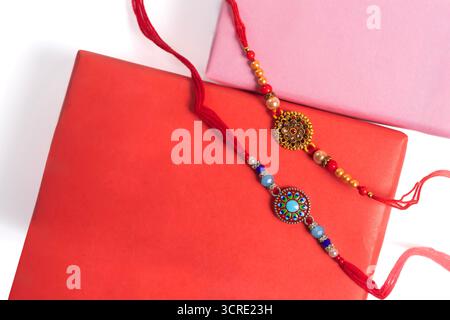 Eine Nahaufnahme wunderschön gestalteter Rakhi-Armreifen, verziert mit bunten Perlen, platziert in leuchtenden rosa und roten Kästen, die die Feier von Ra symbolisieren Stockfoto