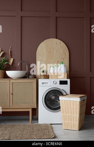 Moderne Waschmaschine, Wäschekorb und Kommode mit Waschbecken im Badezimmer Stockfoto
