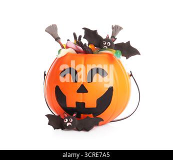 Kessel in Form von Kürbis mit Süßigkeiten für Halloween, Besen und Fledermäuse isoliert auf weißem Hintergrund, Nahaufnahme Stockfoto