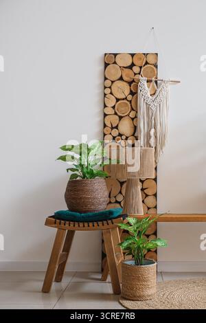 Holzbank, Lampe und Korbgefäße mit Zimmerpflanzen im Inneren des Wohnzimmers Stockfoto