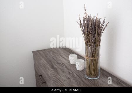 Ein Blick auf eine Vase mit getrockneten Lavendelblüten auf einer rustikalen Holzkommode als Hintergrund. Stockfoto