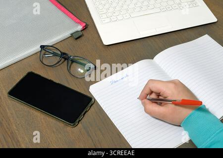 Konzentration der Aufmerksamkeit bei den Hausaufgaben der Schüler. Schuljunge lernen umgeben von modernen Geräten Stockfoto
