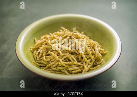 Trofie-Pasta mit Pesto-Sauce in einer grünen Schüssel, die italienische kulinarische Tradition repräsentiert Stockfoto