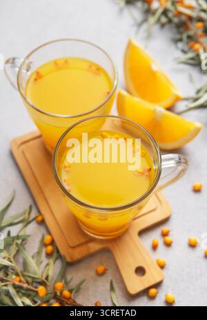 Sanddorn Beeren- und Orangenscheiben, die ein gesundes Kräutergetränk in klaren Tassen schaffen Stockfoto
