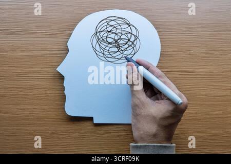 Menschlicher Kopfausschnitt mit einer Hand, die chaotische Kritzeleien zeichnet. Stress, Angst, Verwirrung, psychische Störungen, Depressionen und psychische Probleme. Stockfoto