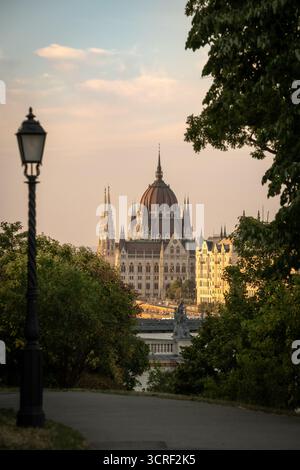 Ungarisches Parlamentsgebäude durch Gartenweg und Lampenträger in der Abenddämmerung - Budapest, Ungarn Stockfoto