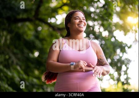 Große junge Frau, die durch den Wald läuft und aussah Stockfoto