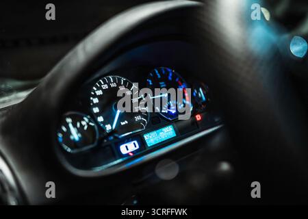 Die Leuchten im Armaturenbrett des Fahrzeugs leuchten blau und zeigen den Tachometer an. Drehzahlmesser. Kraftstoffanzeige. Temperaturanzeige. Und die Kilometeranzeige wird nachts auf dem Bildschirm angezeigt. Unterdrücken Stockfoto