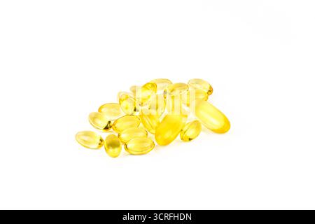Ein Haufen gelber Pillen auf weißem Hintergrund. Die Pillen sind klein und oval. Konzept der Gesundheit und Wellness, da die Pillen wahrscheinlich Vitamine sind Stockfoto