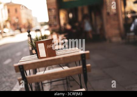 Padova, italien 1. oktober 2025: Straßencafé-Tisch mit Coca-Cola-Serviettenspender für Gäste auf einem sonnendurchfluteten italienischen Bürgersteig, charmante Altstadt von atmos Stockfoto