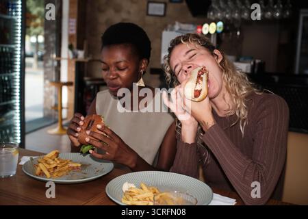 Verschiedene Freundinnen genießen Fast Food im Restaurant Stockfoto