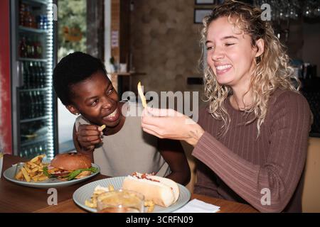 Verschiedene Freunde, die Fast Food genießen und Pommes frites teilen Stockfoto