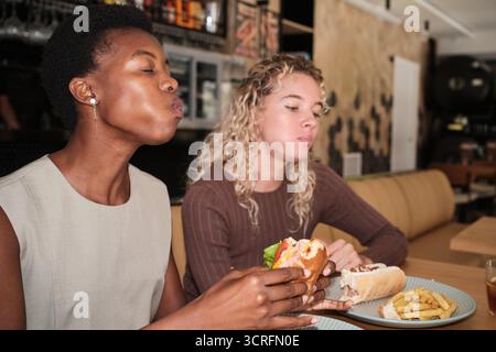 Verschiedene Freundinnen essen Fast Food im Restaurant Stockfoto