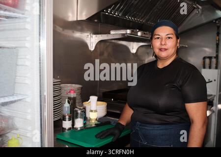Frau, die in der professionellen Küche lächelt Stockfoto