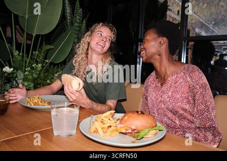 Verschiedene Freundinnen essen Burger und Hot Dog Stockfoto