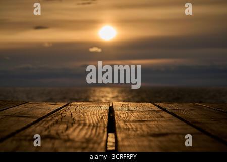 Ein ruhiger Sonnenuntergang über dem ruhigen Wasser von einem wunderschönen hölzernen Pier Stockfoto