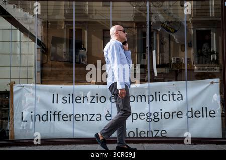Lamezia Terme, Italien. 30. September 2025. Ein Demonstrant läuft während der Kundgebung an einem Banner vorbei, auf dem steht: „Schweigen ist Komplizenschaft“. Eine friedliche Sitzung aus Protest, die von Aktivisten verschiedener Verbände organisiert wurde, um in Lamezia Terme gegen die Entscheidungen der Regierung über Palästina zu protestieren. (Foto: Valeria Ferraro/SOPA Images/SIPA USA) Credit: SIPA USA/Alamy Live News Stockfoto