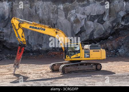 Ein Komatsu PC490 LC Raupenbagger mit hydraulischem Hammer (Schlaghammer), der vulkanisches Basaltgestein in einem Steinbruch am Ätna spaltet Stockfoto