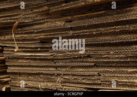 Eine horizontale Nahaufnahme eines großen Kartonstapels, die die raue, gewellte Textur und die komprimierten Schichten zeigt. Stockfoto