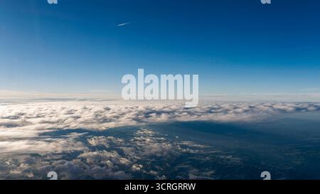 Über den Wolken: Aus der Vogelperspektive auf den klaren blauen Himmel und den Horizont von Einem Flug Stockfoto