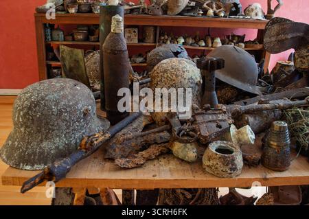 Relikte aus dem Zweiten Weltkrieg, darunter Helme, Waffen und Munition, werden ausgestellt, um die Geschichte zu bewahren und diejenigen zu ehren, die dienten. Stockfoto