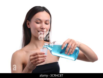 Lächelnde junge Frau, die vor weißem Hintergrund Mundwasser in die Kappe gießt. Mundhygiene Stockfoto