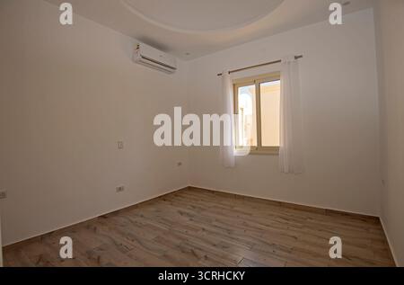 Leeres leeres Schlafzimmer in unmöbliertem Wohnheim mit Fenster und Vorhängen Stockfoto