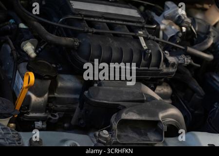 Detaillierte Nahaufnahme eines Fahrzeugmotors mit Luftansaugung, Schläuchen und Messstab für Fahrzeugwartung und -Technik Stockfoto