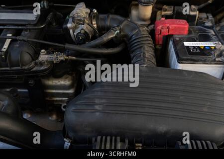 Nahaufnahme eines Motorraums eines Autos mit sichtbarer Batterie, Luftansaugsystem und Motorkomponenten. Ideal für Automobil-, Reparatur- und Wartungszwecke des Stockfoto