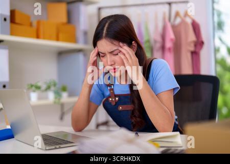 Junge asiatische Frau, die zu Hause arbeitet, erlebt Kopfschmerzen Frustration Management Online-Shop-Geschäft Unternehmer Burnout psychische Gesundheit Stockfoto