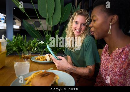 Verschiedene Freundinnen unterhalten sich lächelnd und genießen das Essen Restaurant Stockfoto