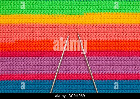 Mehrfarbiger, handgefertigter Stoff mit zwei Stricknadeln. Stockfoto