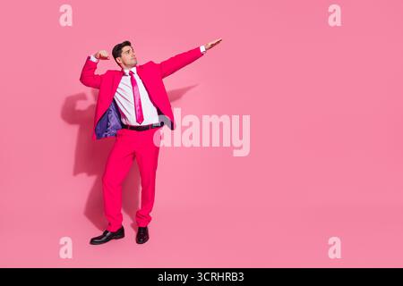 Selbstbewusster junger Mann im auffälligen rosafarbenen Anzug, der stilvoll vor hellem Hintergrund posiert und Charme und moderne Attitüde ausstrahlt Stockfoto