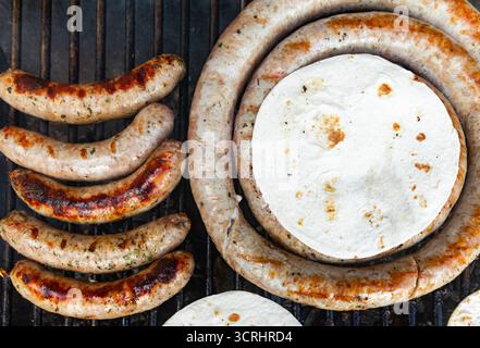 Gebratene hausgemachte Bratwürste mit Fladenbrot darauf. Stockfoto