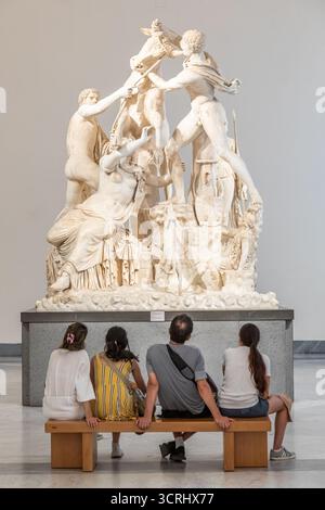 NEAPEL, ITALIEN – AUGUST 2025: Eine Familie sitzt auf einer Bank und betrachtet die kolossale Marmorstatue Farnese Bulle im Archäologischen Museum von Neapel - Stockfoto