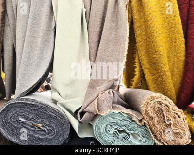 Fabric rolls displaying various colors and textures of wool and tweed textiles, ready for tailoring and fashion projects Stockfoto