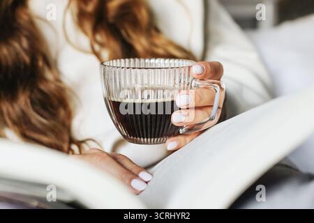 Eine Frau hält eine Tasse Kaffee in der Hand. Entspannen Sie sich mit einem warmen Heißgetränk. Lebensstil mit Koffein-Energie-Moment. Weibliche Hände Nahaufnahme mit Getränk. Stockfoto