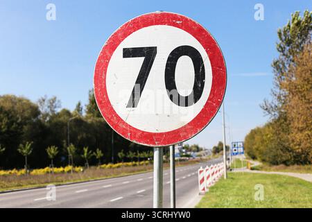 Verkehrszeichen Geschwindigkeitsbegrenzung siebzig. Verkehrssymbol am Straßenrand mit Asphalt. Sicherheitsdetails für den Straßenverkehr. Straßenansicht mit klarem Himmel im Hintergrund. Stockfoto