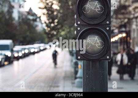 Nahaufnahme des ausgeschalteten Radverkehrslichts, das auf der belebten Stadtstraße beleuchtet ist und tagsüber Radfahrer und Fußgänger pendeln Stockfoto