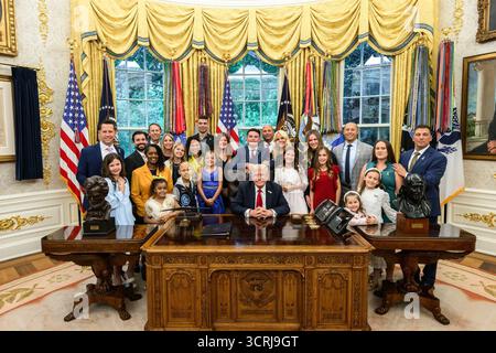 US-Präsident Donald J. Trump posiert mit Familien und Kindern, nachdem er im Oval Office des Weißen Hauses eine Executive Order unterzeichnet hat, um die amerikanische KI-Innovation für die Krebsforschung und -Prävention bei Kindern zu nutzen. Washington, D.C., 30. September 2025. Bild mit freundlicher Genehmigung des Weißen Hauses. Stockfoto