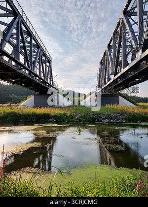 Zwei parallele Brücken über den Fluss. Schwindender perspektivischer Blick auf zwei alte Fachwerkstühle über dem Fluss. Stockfoto