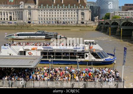 London, England, Großbritannien - 4. Juli 2025: Touristen warten auf der Anlegestelle auf ein Touristenboot, das an der Themse im Zentrum Londons anlegt Stockfoto
