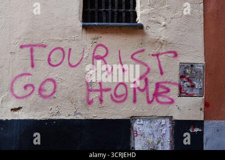 "Tourist go Home" Graffiti, Protestschreiben gegen Massentourismus, an einer Mauer in einem typischen Caruggio (enge Gasse), Genua, Ligurien, Italien Stockfoto