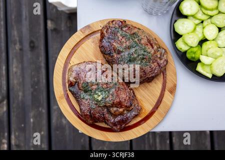 Frisch gegrillte saftige Rindersteaks auf hölzernem Schneidebrett, Blick von oben Stockfoto
