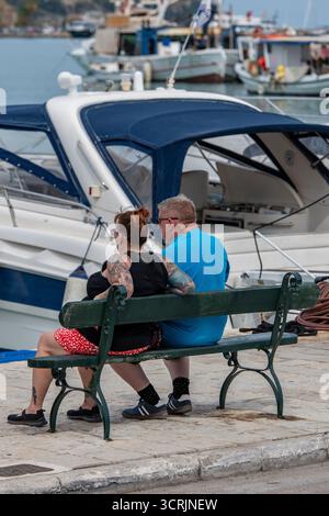 Ältere oder ältere Ehepaare mittleren Alters sitzen zusammen auf einer Bank an der Seite eines Hafens oder Yachthafens. Stockfoto
