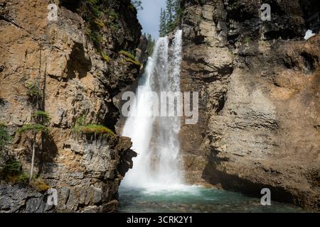 Der Wasserfall stürzt kraftvoll in eine felsige Schlucht mit türkisfarbenem Wasser. Stockfoto